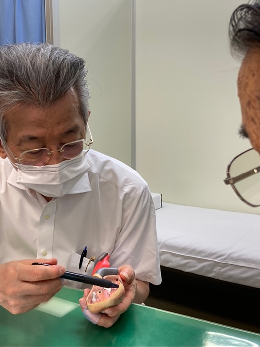 心臓の模型を手に患者様に説明する院長先生。